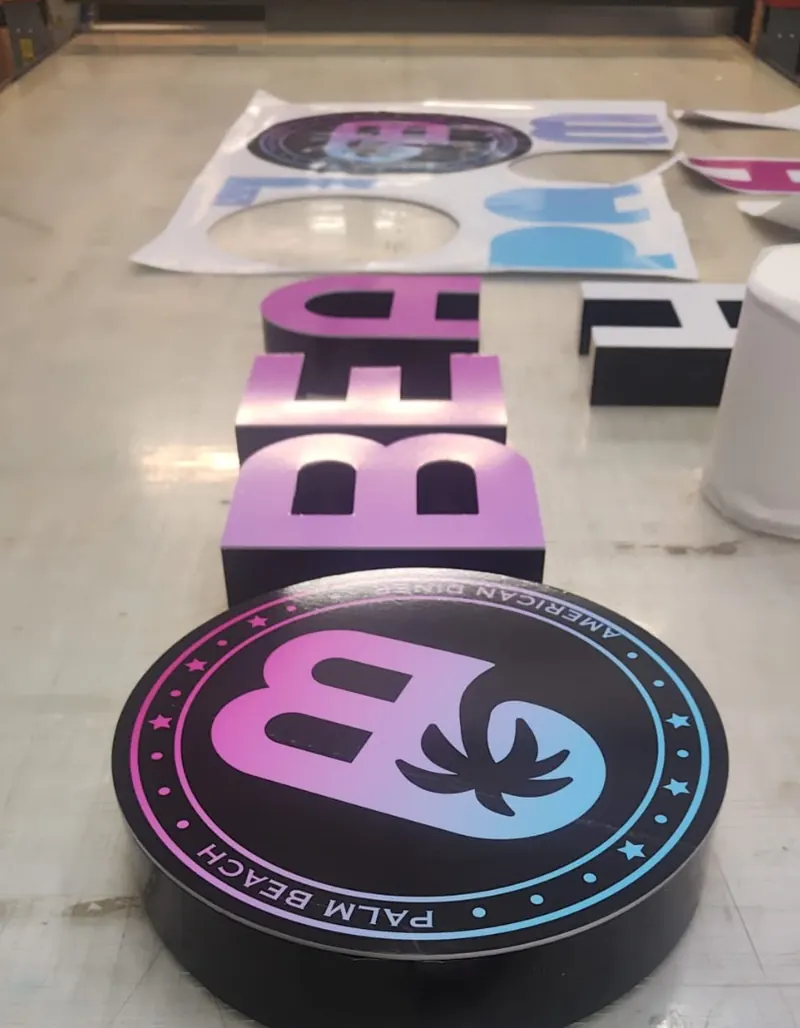 À l'atelier : lettres boîtiers et caisson rond Palm Beach en préparation sur l'établi