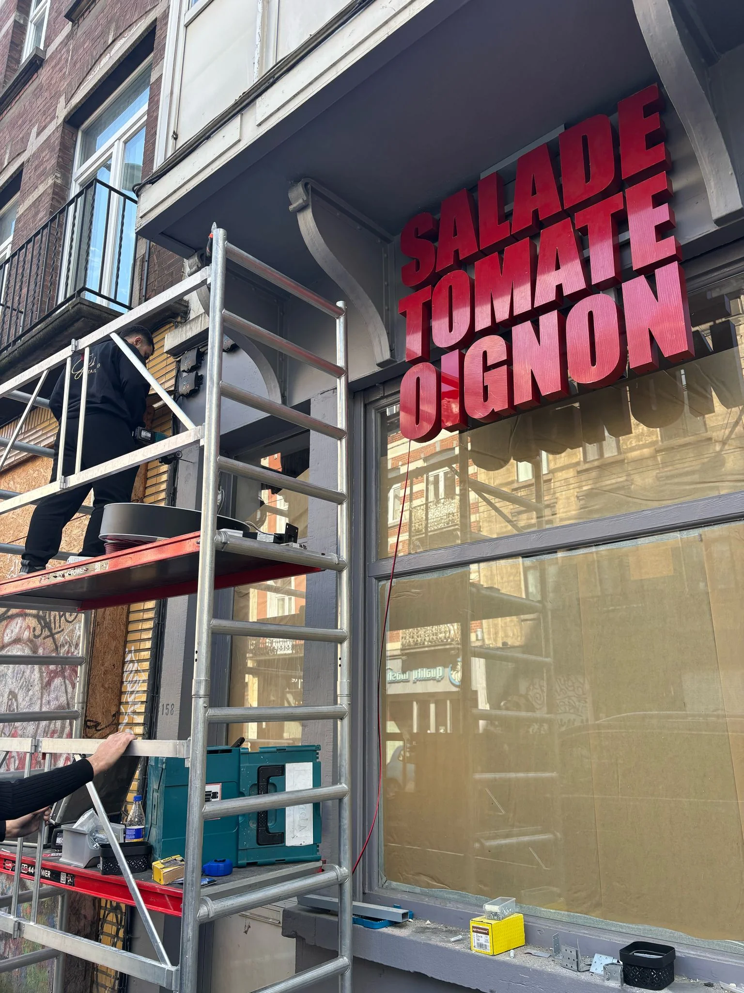 Installation enseigne Salade Tomate Oignon sur échafaudage